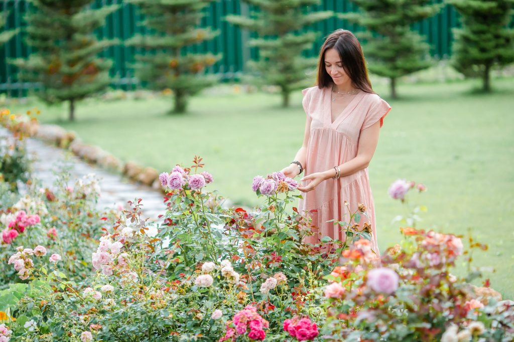 Young girl in a flower garden among beautiful roses. Smell of roses